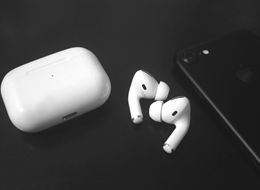 White AirPods and charging case on a black background